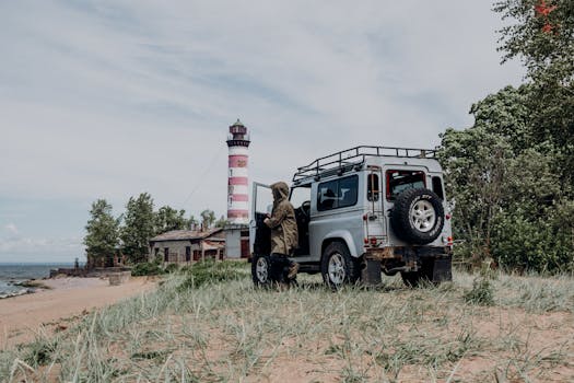 Adventurer with vehicle near Shepelyovsky Lighthouse along a scenic coastline.
