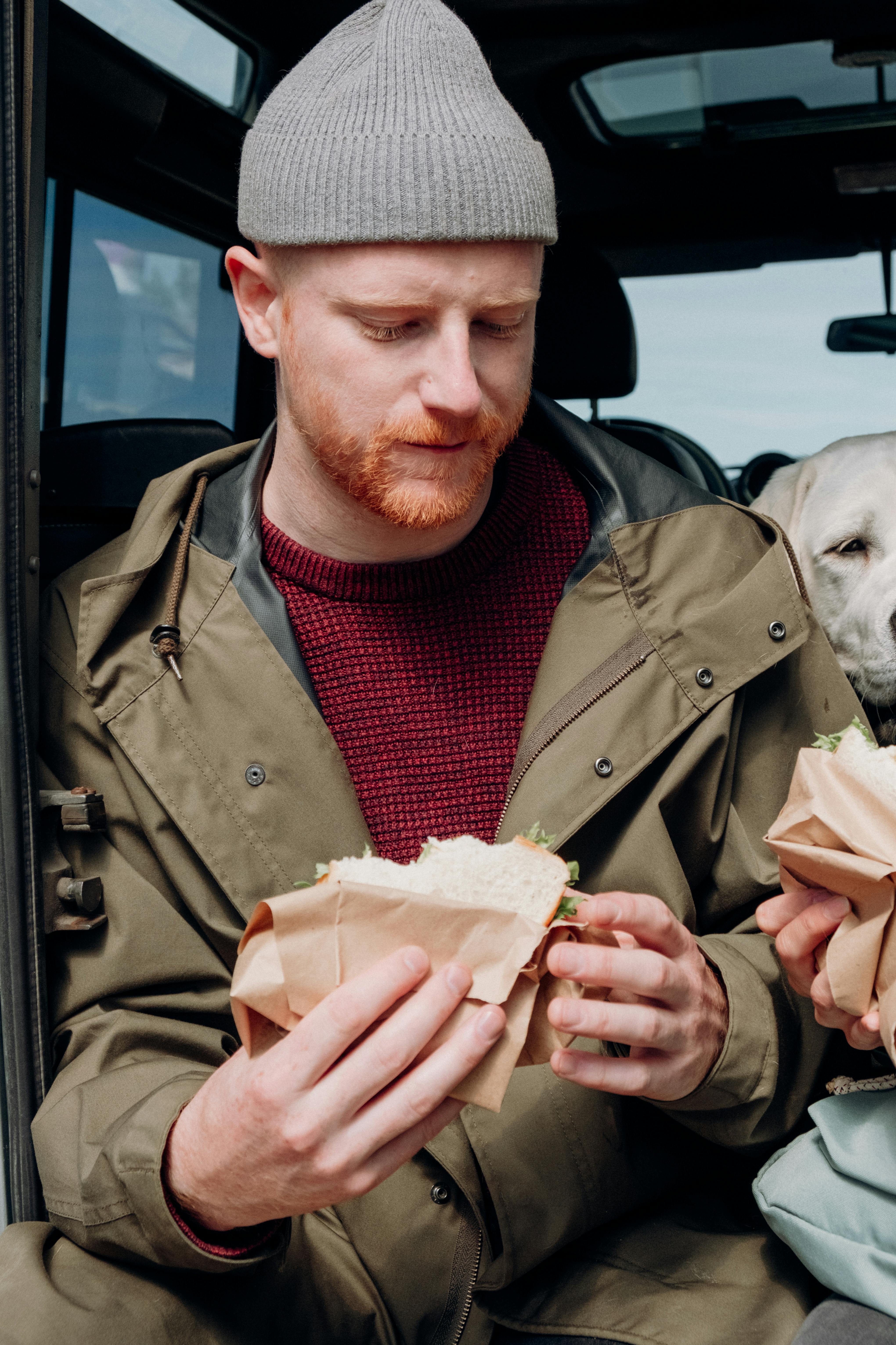 man in brown coat holding bread