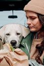 一位戴着无檐帽的女士在户外和她的拉布拉多猎犬分享三明治