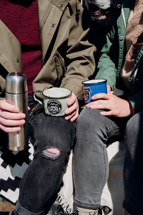 Person in Brown Jacket Holding Black and White Mug