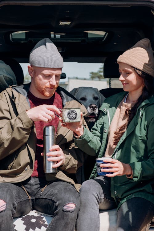 Woman in Green Jacket Holding White and Black Mug