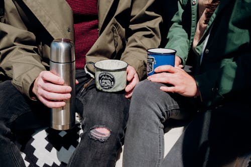 Person Holding Blue and Silver Can