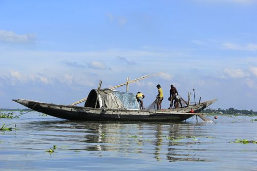 Free Fishermen using a traditional boat on a serene river in Bangladesh, capturing daily life. Stock Photo