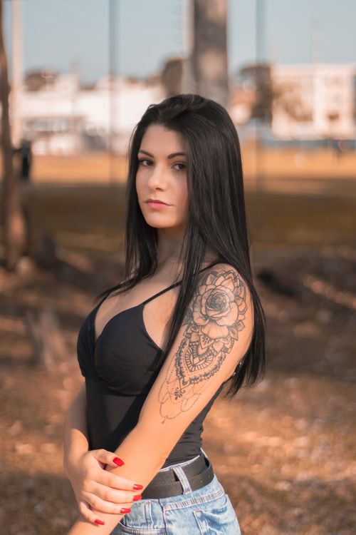 Free Portrait of a young woman with tattoo posing outside, showcasing fashion style. Stock Photo