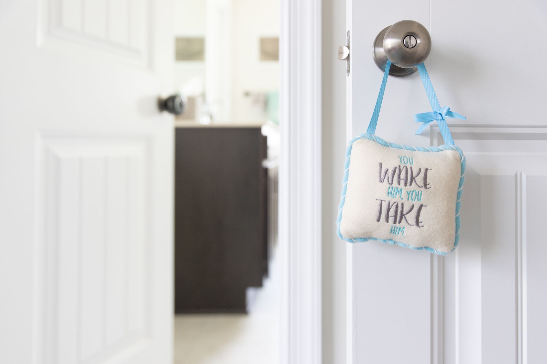 A charming door hanger with playful text in a modern baby nursery setting.
