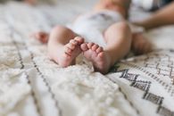 柔软的特写捕捉到纯真：新生儿的脚放在图案毯子上