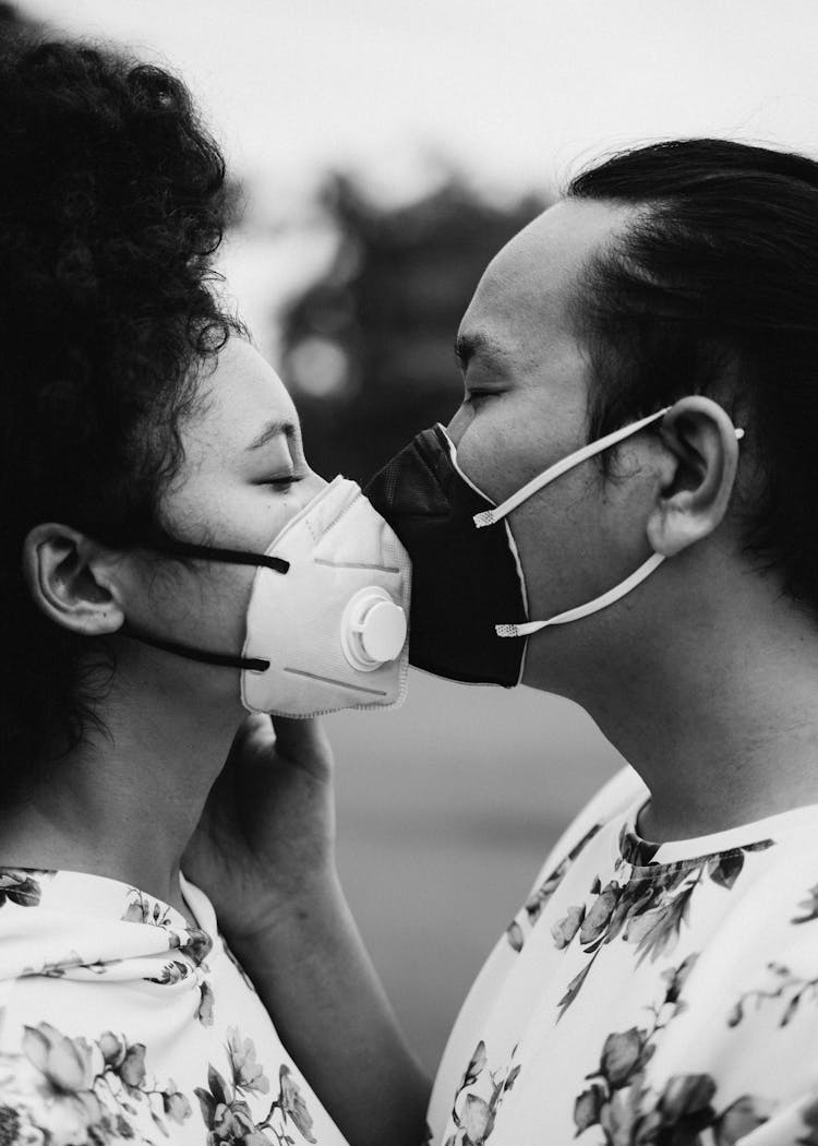 Grayscale Photo Of Couple With Face Masks Kissing