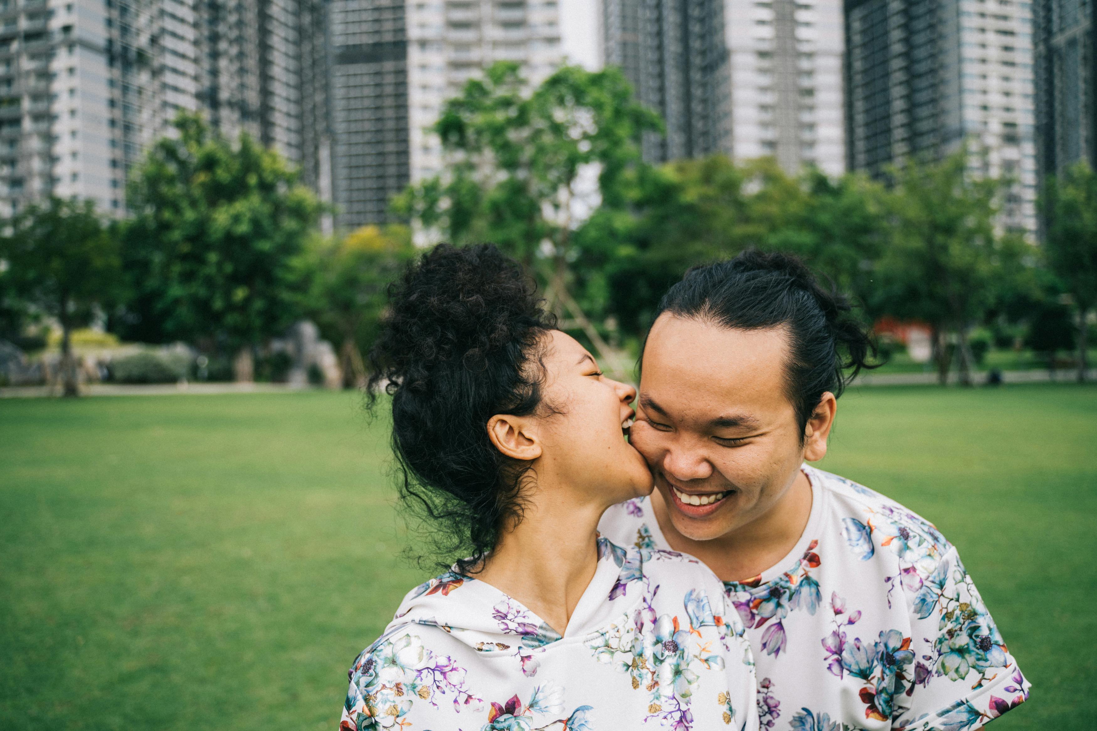 一对幸福的情侣在绿植环绕、高楼林立的公园里欢笑