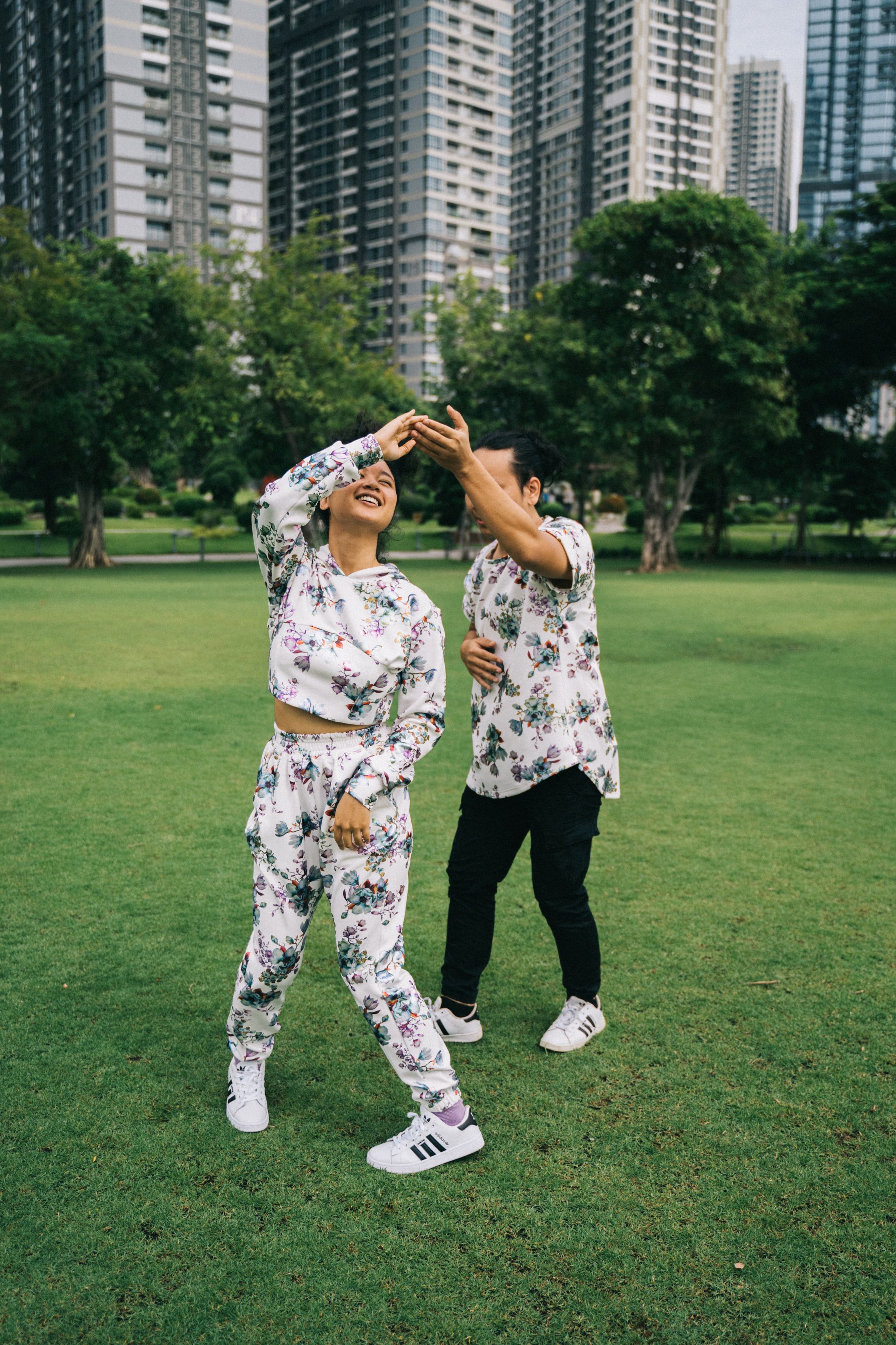 一对幸福的夫妇在阳光明媚的一天，于城市摩天大楼前的绿色草坪上跳舞