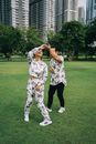 一对幸福的夫妇在阳光明媚的一天，于城市摩天大楼前的绿色草坪上跳舞