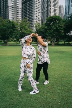 一对幸福的夫妇在阳光明媚的一天，于城市摩天大楼前的绿色草坪上跳舞