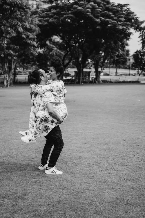 Grayscale Photo of a Man Carrying a Woman