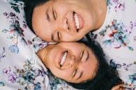 一对开朗的亚洲夫妇微笑着躺在地上，穿着印花衣服的特写镜头