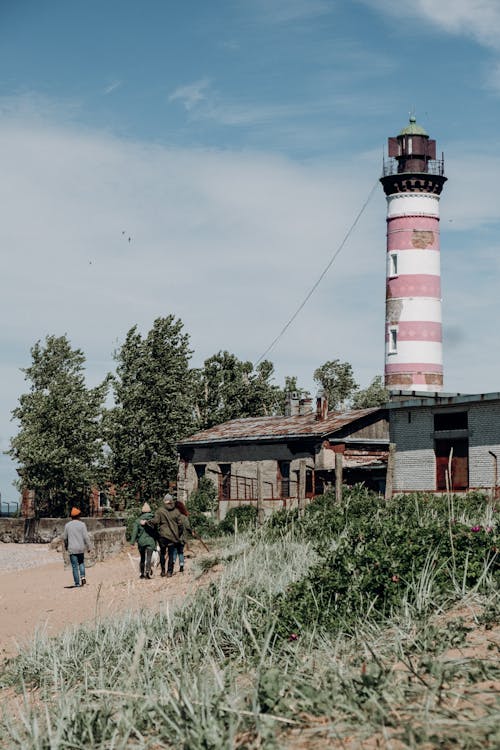 People Walking Near Red and White Lighthouse