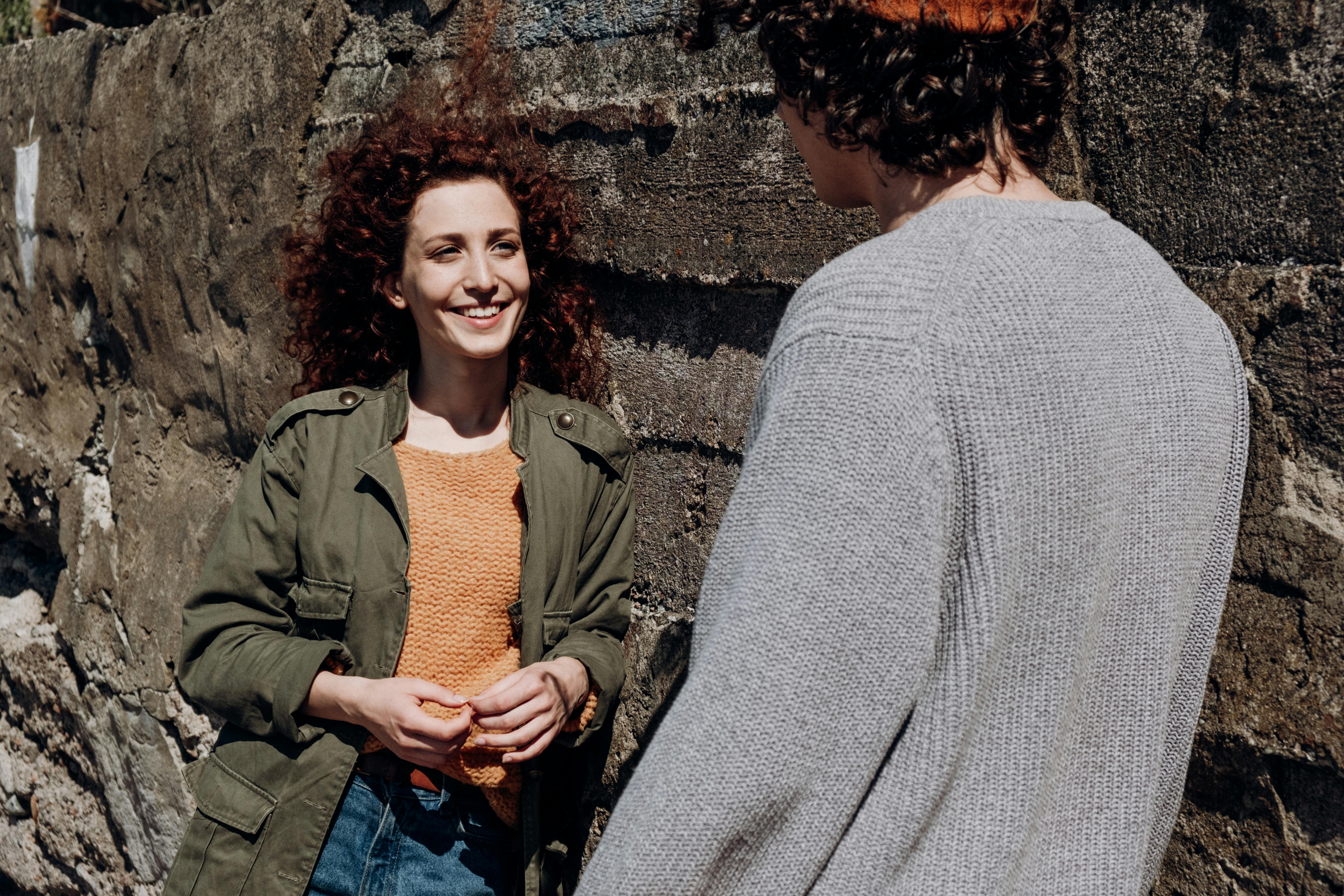 Free Two adults enjoying a relaxed conversation outdoors on a sunny day. Stock Photo