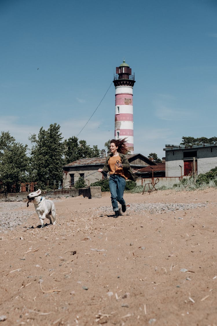 A Woman Running With Her Dog On The Beach