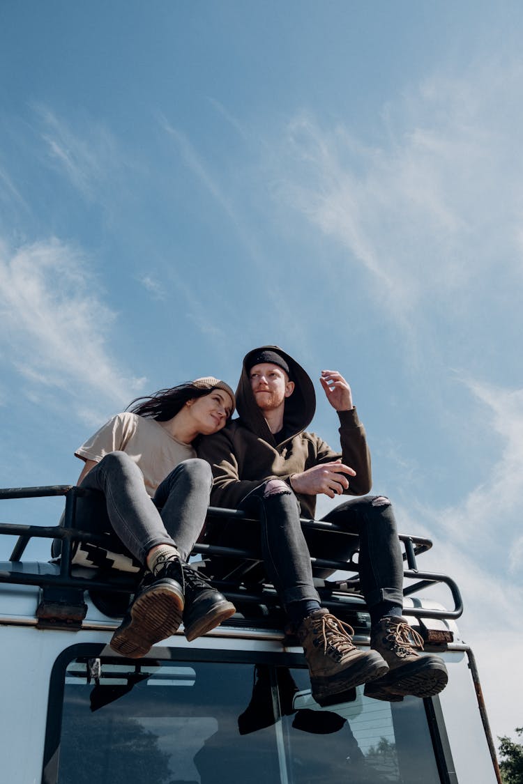 Low Angle Shot Of Couple Sitting On Top Of An Off-road Truck 