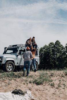 Young friends gather around an SUV in the countryside during a road trip. Perfect for travel and adventure themes.