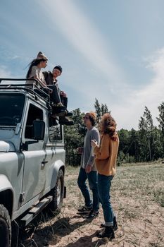 Group of friends enjoying a sunny day with an off-road vehicle, bonding outdoors in nature.