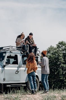 Group of friends enjoying leisure time on a road trip with an off-road vehicle outdoors.