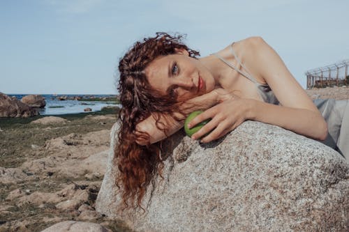 Een Vrouw In Een Grijze Jurk Poseren Op Een Rots Op Het Strand