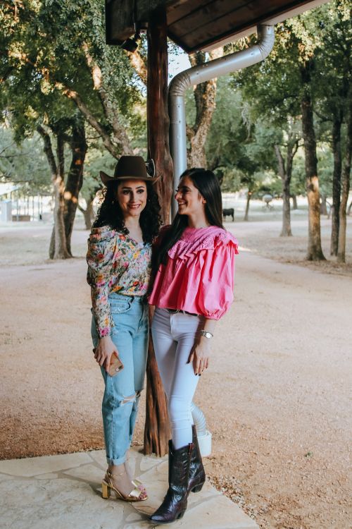 Free Full body of cheerful young ethnic female friends standing in yard of house near park with bright smile in daytime Stock Photo