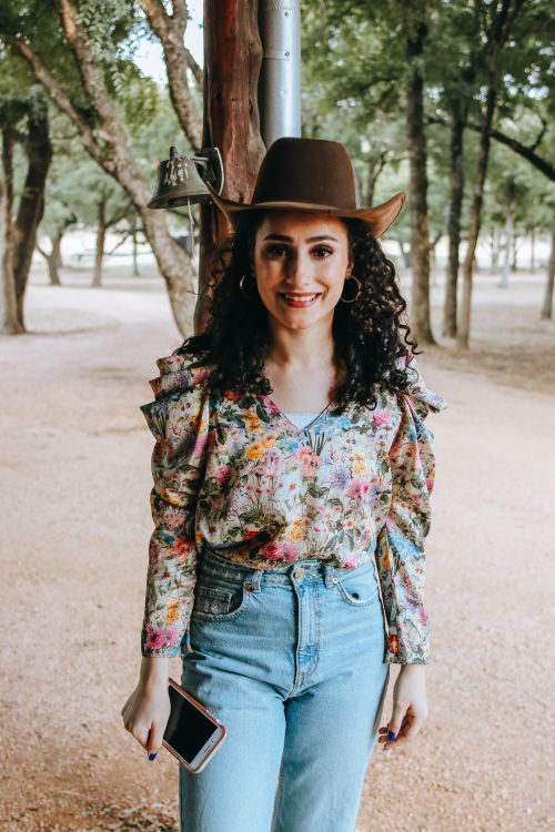 Free Happy female with bright makeup in stylish blouse and denim with smartphone looking at camera in sunny park Stock Photo