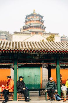 游客在北京颐和园的传统建筑附近坐着