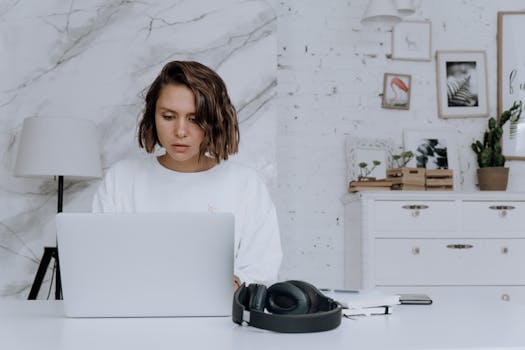 A woman focuses on her laptop in a modern home office setting, exemplifying remote work.