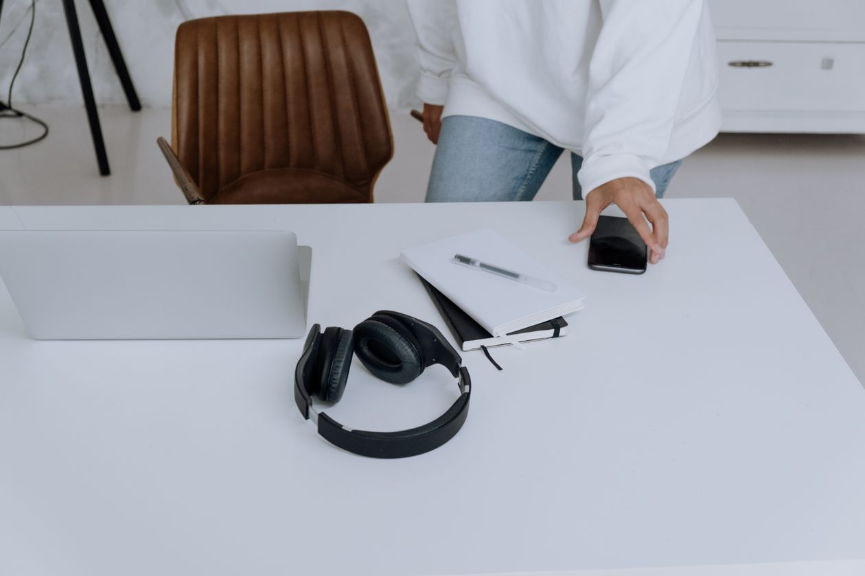 A laptop, headphones and notebook on a working desk