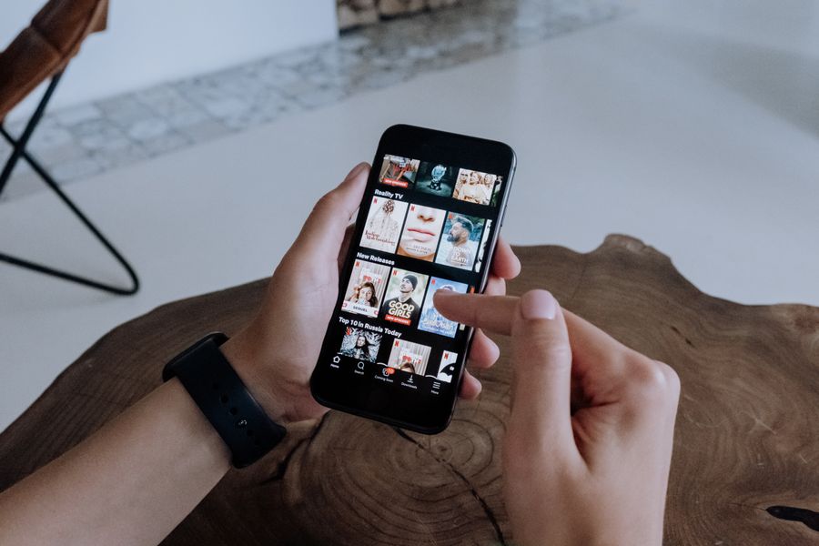 A person holding a smartphone browsing short shows on a streaming app indoors