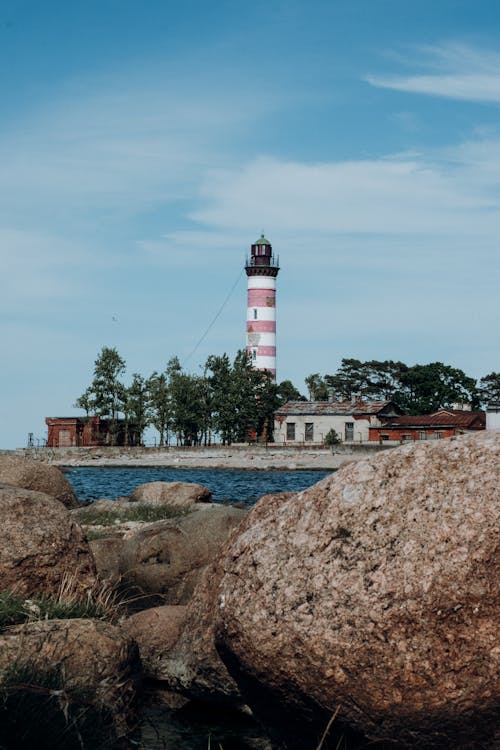 Phare Blanc Et Rouge Près De Maison Blanche Et Brune Sous Le Ciel Bleu