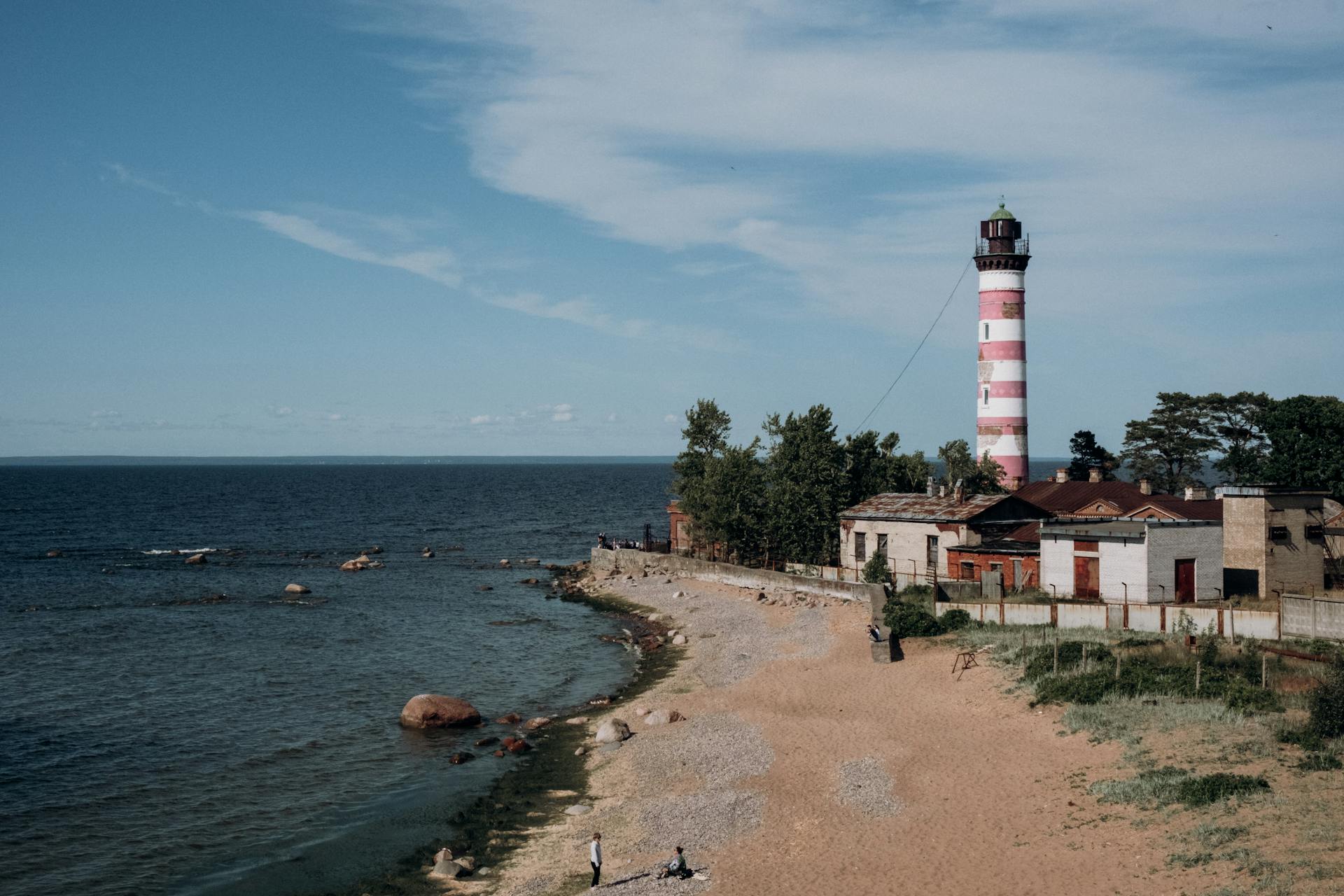 A picturesque lighthouse on a rocky coast with a clear blue sky overhead.