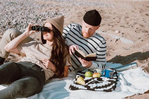 Free A couple enjoys a relaxing day on the beach with snacks, a good book, and binoculars for sightseeing. Stock Photo