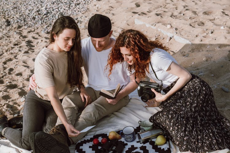 People Sitting On A Blanket While Looking At A Picture