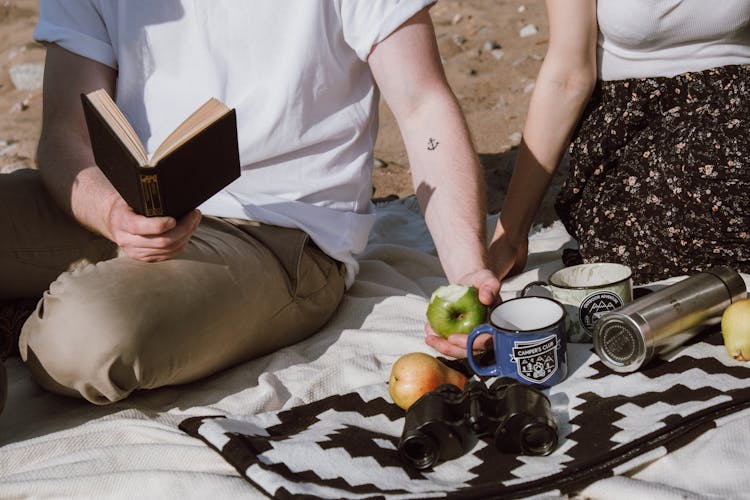 Person Holding An Apple And A Book