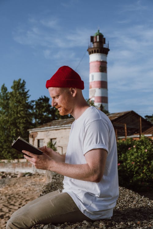 Hombre En Camiseta Blanca De Cuello Redondo Y Gorro De Punto Rojo Con Smartphone Negro