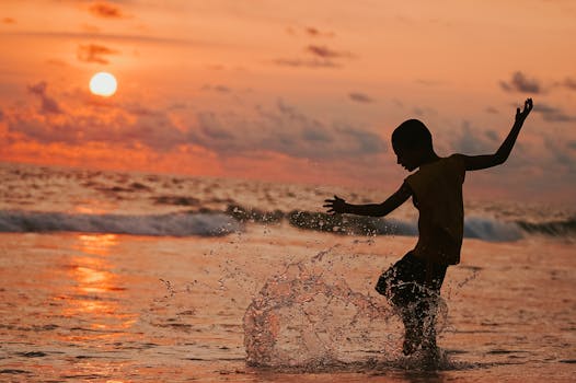 A child joyfully splashing in the ocean waves during a vibrant sunset, capturing pure happiness and freedom.