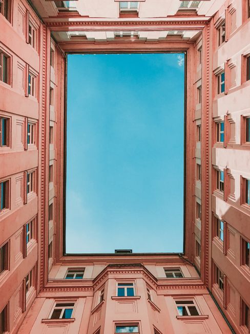 A unique worm's eye view of a Budapest courtyard showcasing elegant architecture and a vivid blue sky.