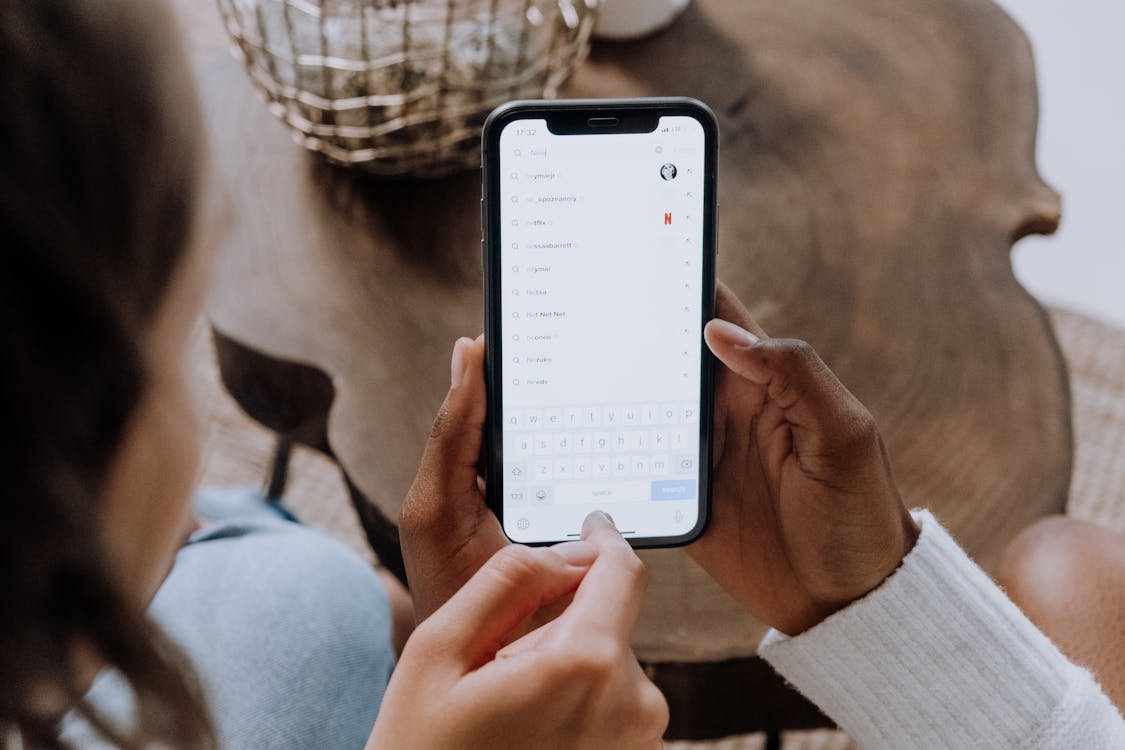 Close-up of two people looking at a mobile phone displaying TikTok search screen.