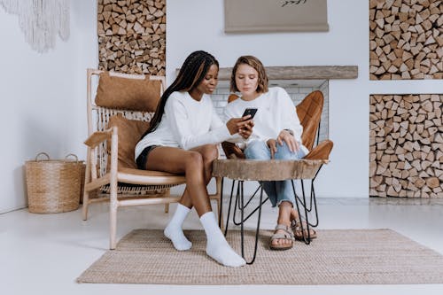 2 Women Sitting on Brown Wooden Chair