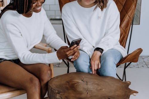 Free Woman in White Long Sleeve Shirt and Blue Denim Shorts Sitting on Chair Stock Photo