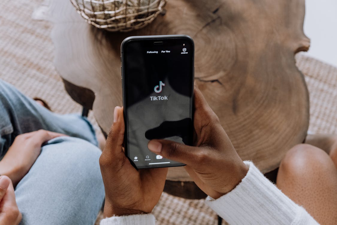 Hand holding smartphone with TikTok logo on screen.