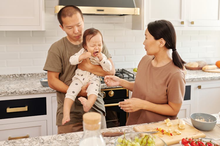 Man Carrying A Baby Beside A Woman