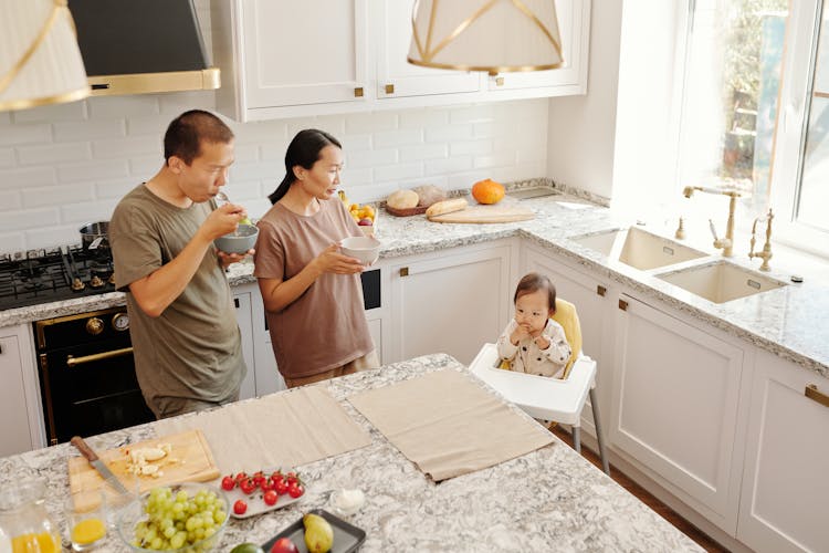 Man And Woman Eating While Looking At A Baby