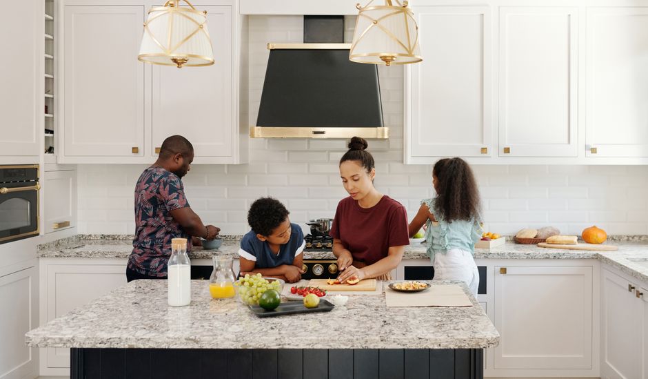 Family enjoying a cooking session together in a bright modern kitchen setting.