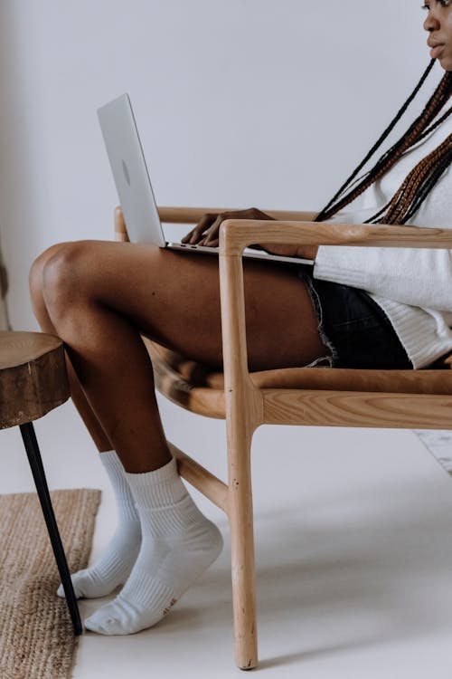 Woman in Black Panty and White Socks Sitting on Brown Wooden Chair