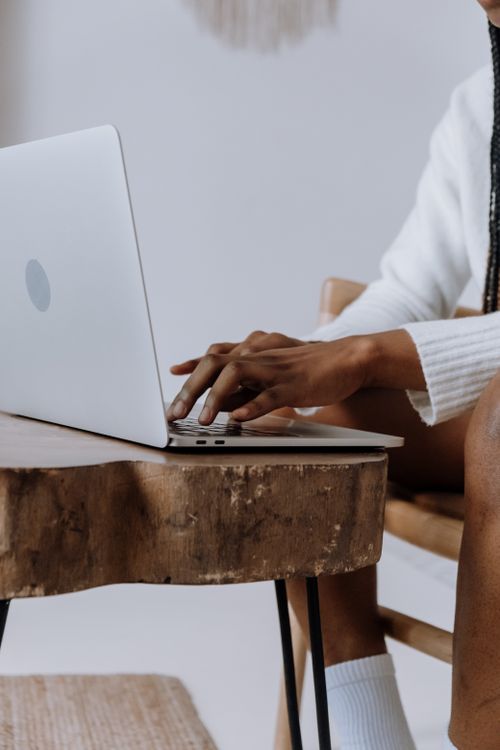 Free A person typing on a laptop at a rustic wooden table indoors, depicting modern technology use. Stock Photo
