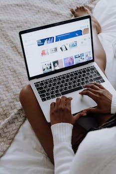A woman browsing digital designs on a laptop while sitting comfortably at home.
