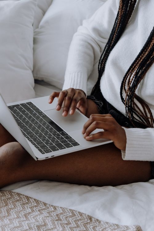Free A woman using a laptop sitting comfortably at home, focused on typing. Stock Photo
